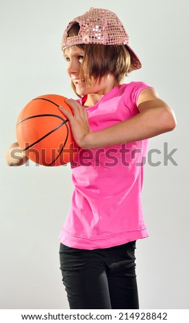Little 10 years old girl exercising with a ball, making a basketball throw. Sports active childhood lifestyle concept.