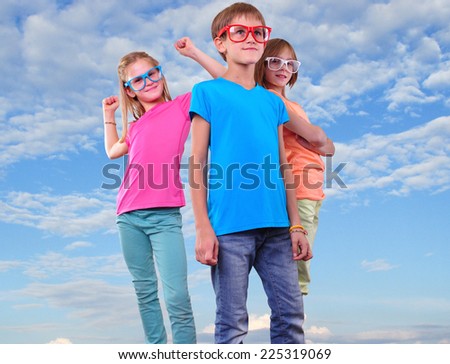 Group of happy friends wearing eyeglasses against blue cloudy sky . Childhood, happiness, active lifestyle concept