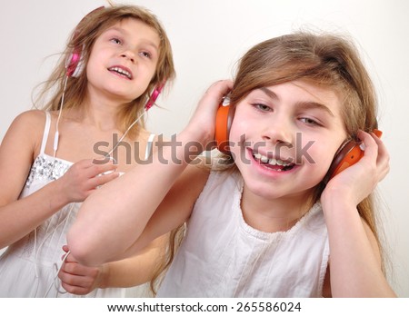 portrait of two little girls with headphones  listening to music and having fun