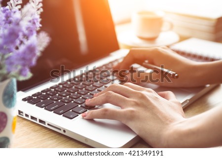 A woman is working by using a laptop computer on table. Hands typing on a keyboard. Selective focus