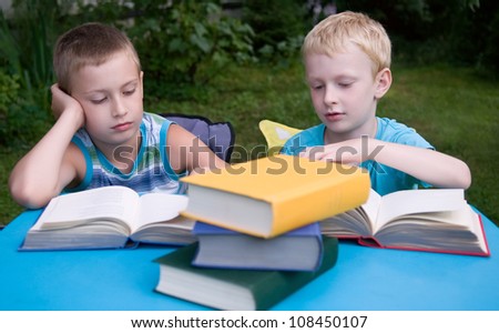 8-year and 6-year boys reading books outdoors