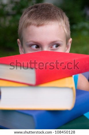 8-year schoolboy and stack of books outdoors