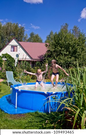 two boys jumping and splashing in swimming pool outdoors