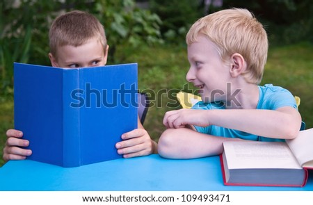 8-year schoolboy and 6-year preschooler reading books and discussing outdoors