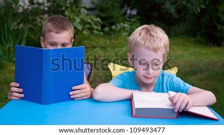 8-year and 6-year boys reading books outdoors