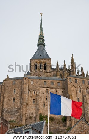 French flag in front of Mont Saint-Michel. The Mont Saint-Michel is a tidal island in Normandy and one of the most visited tourist sites in France.