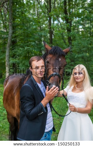 Beautiful bride and groom with a horse in the forest. Focus on a groom and a horse.