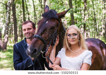 Beautiful bride and groom with a horse in the forest