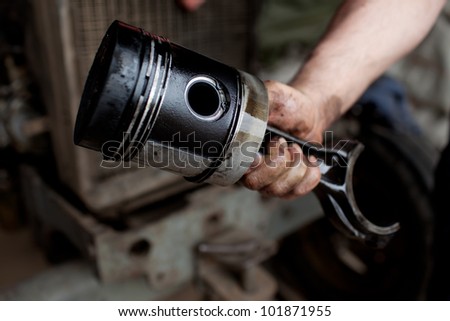Car mechanic holding engine piston.