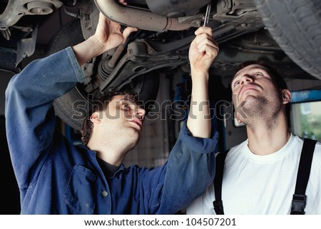 Mechanics repairing car in garage under the car.