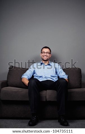 Happy businessman sitting on sofa in blue shirt