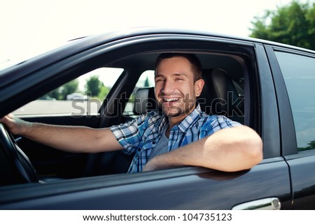 Portrait of young handsome man smiling in his own car