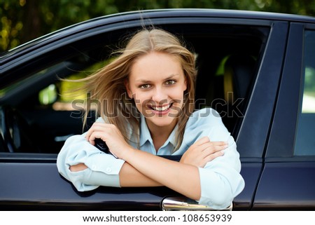 Young happy driver sitting in car with key in hand