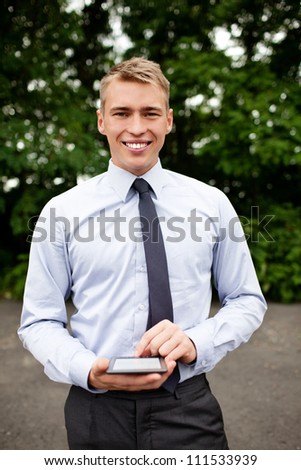 Young businessmanwith ebook reader standing outdoor  smiling