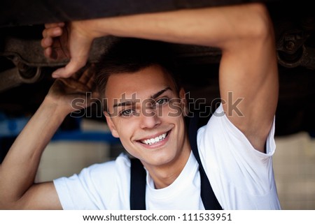 Car  mechanic posing under the car smiling.