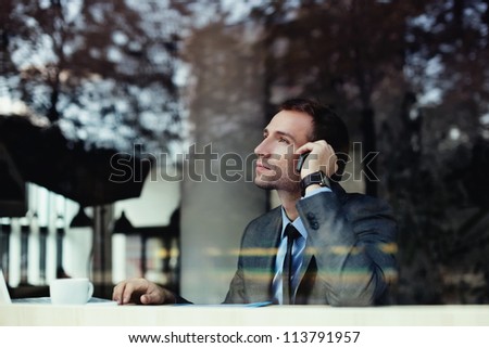 Handsome businessman talking on the phone in coffee shop.