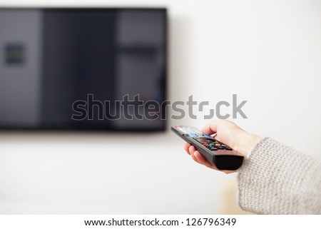 Female hand holding TV Remote Control