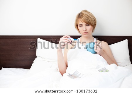 Sick woman measuring body temperature in bed.