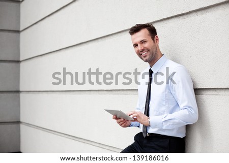 Happy, businessman standing outside the office with digital tablet