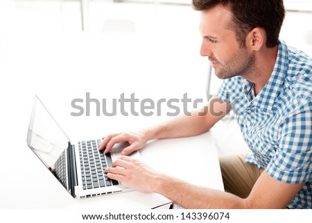 Happy handsome man working with laptop in office