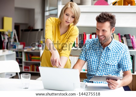 Two bookshop managers working on laptop.