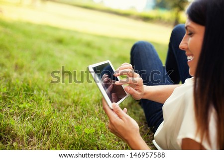 Happy woman using tablet outdoor laying on grass