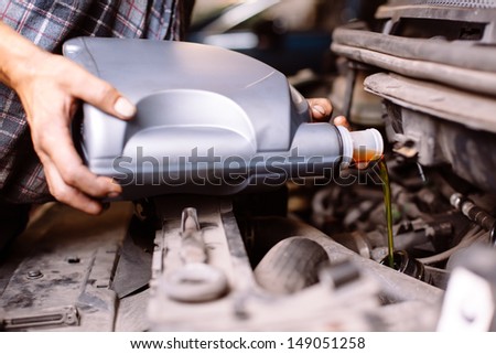 Car mechanic changing engine oil