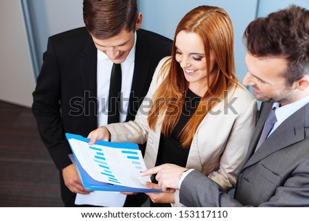 Three business people talking about company performance and analysing chart during meeting