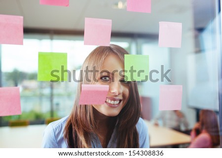 Happy female employee smiling through  window in the office