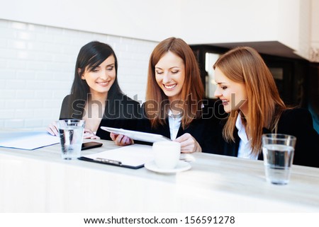 Three corporate businesswoman meeting in cafe.