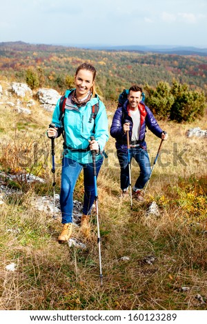 Young couple hiking in nature with sticks. Nordic walking
