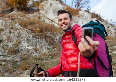 Happy couple hiking with backpacs and sticks in mountains