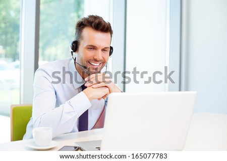 Happy Consultant With Headset Looking At Laptop