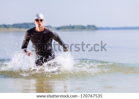 Triathlon swimmer splashing around while running out of water