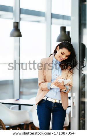 Young attractive woman writing down in her nnotepad