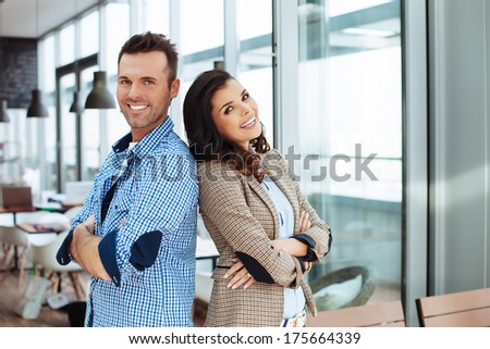 Young smiling couple standing back to back in a cafe