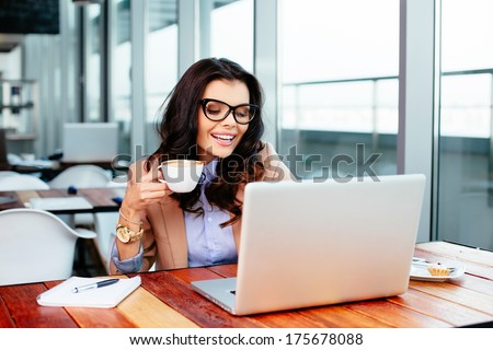 Young woman sipping coffee and using her laptop