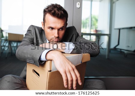 Young laid off manager sitting down with a carton