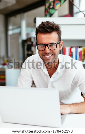 Male student with geek glasses in front of his laptop