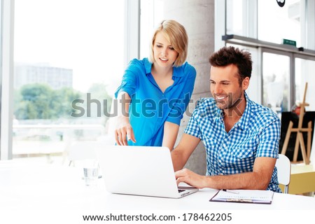 Young web designers looking at a laptop and discussing
