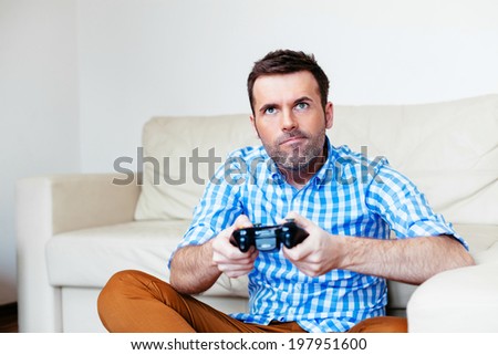 Young adult sitting on the floor and playing a game console