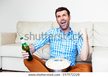 Young sports fan watching a game and celebrating his team victory