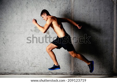 Photo of a running muscular sportsman on a concrete background