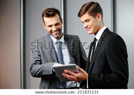 Two young managers talking and looking at a tablet