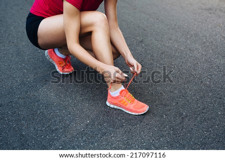 Photo of a female jogger lacing her running shoes