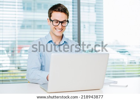 Happy young man typing on laptop