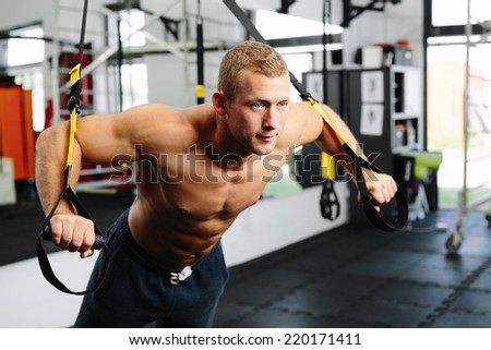 Photo of a young muscular athlete during a suspension training
