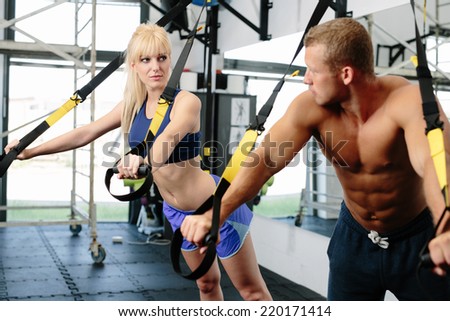 Photo of a muscular couple working out on suspension straps