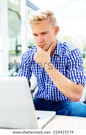 Pensive young man looking at laptop outdoors