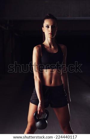 Slim female bodybuilder sculpting her arm with a kettlebell